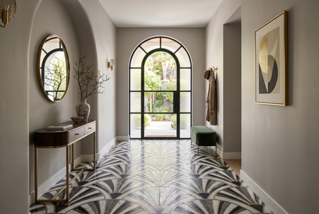 Art Deco house hallway with geometric floor tiles, arched doorway, and console table.