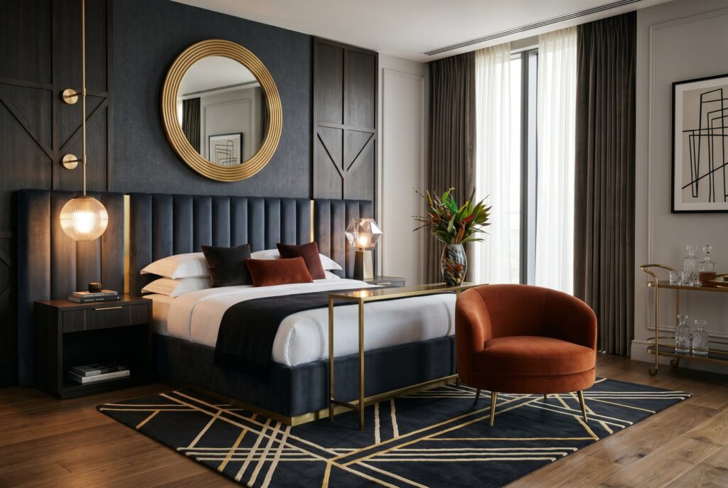 Modern Art Deco bedroom with curved chair, geometric rug, and circular mirror accents. 