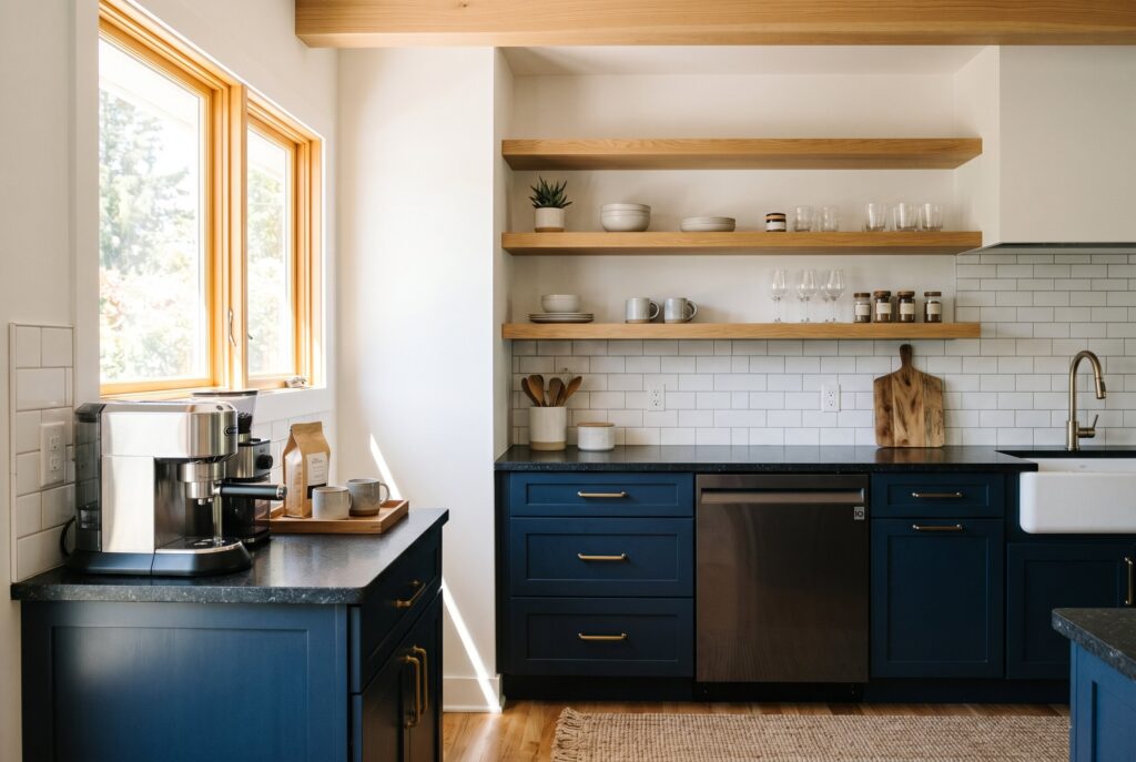 Bright navy kitchen with open wood shelving, farmhouse sink, and black stone countertops.