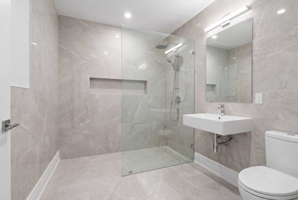 Floor to ceiling tile shower walls with large format porcelain tile and glass partition.
