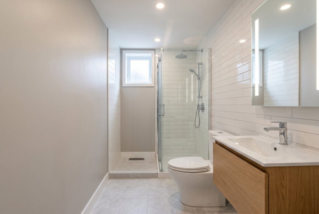 Linear galley basement bathroom layout with vanity, toilet, and shower along one wall.