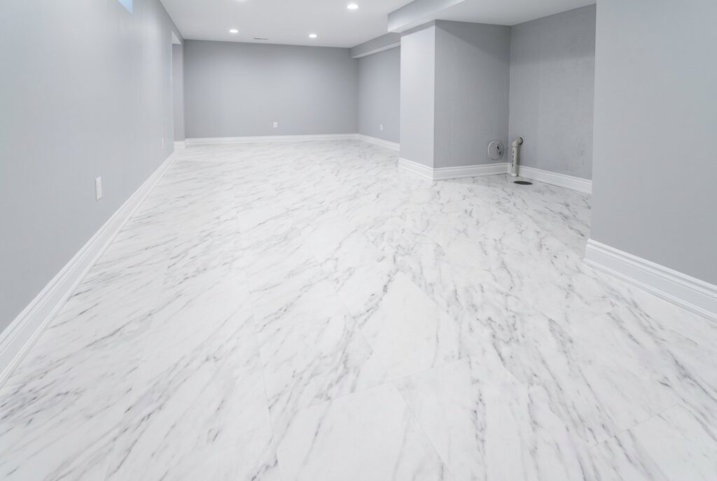 Engineered vinyl plank flooring installation over concrete basement slab with layered construction.