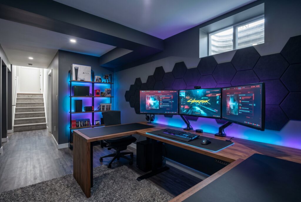 Gamer basement lounge with LED lighting, triple monitor setup, and acoustic wall panels.