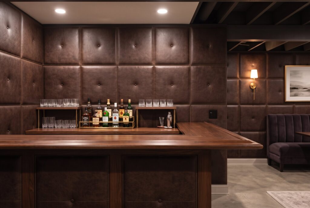 Upholstered faux leather wall panels behind basement bar creating luxury lounge atmosphere.