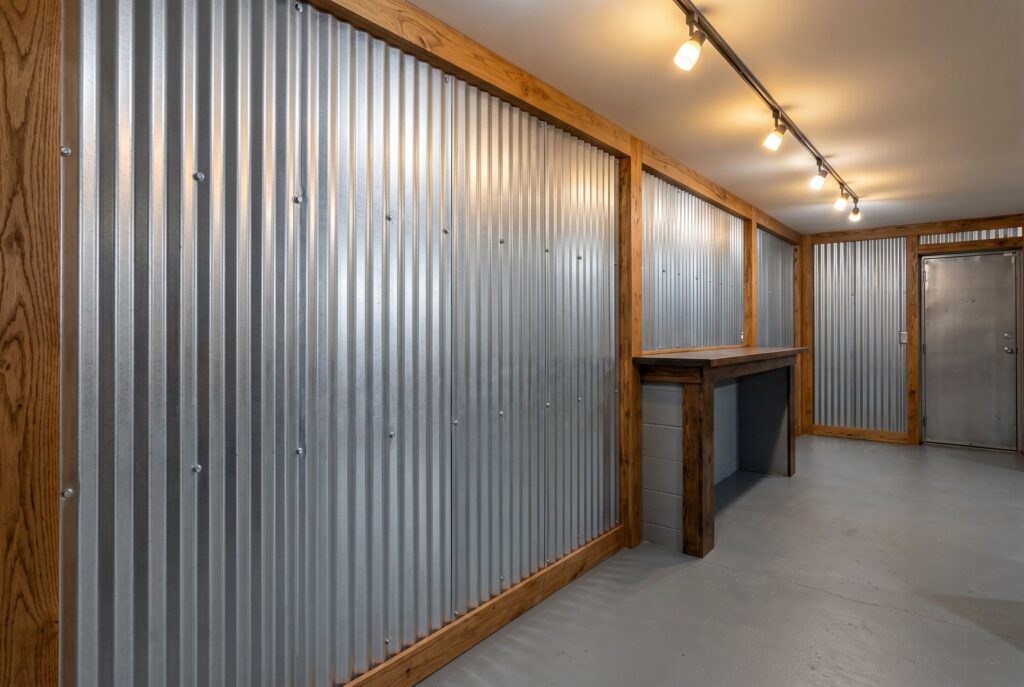 Corrugated metal wall panels with industrial basement workshop and track lighting. 
