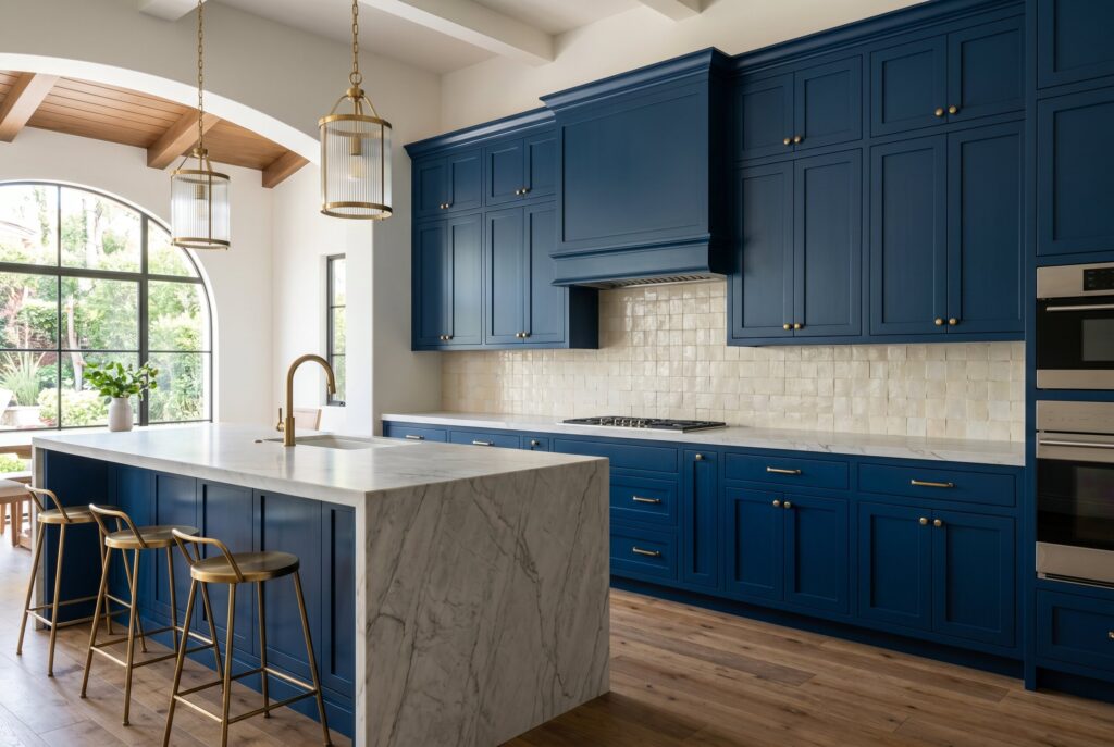 Midnight Blue kitchen cabinets with marble waterfall island, brass lighting, and arched window detail.