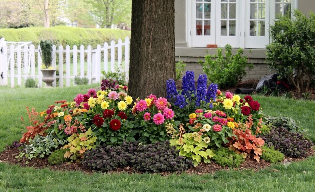 Native woodland wildflowers beneath mature tree creating natural shade garden design. 