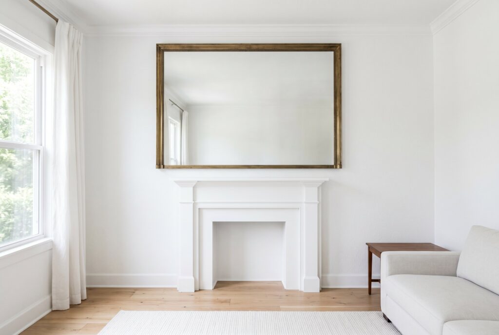 Elegant white living room with decorative wall molding, fireplace, and classic panel detailing.
