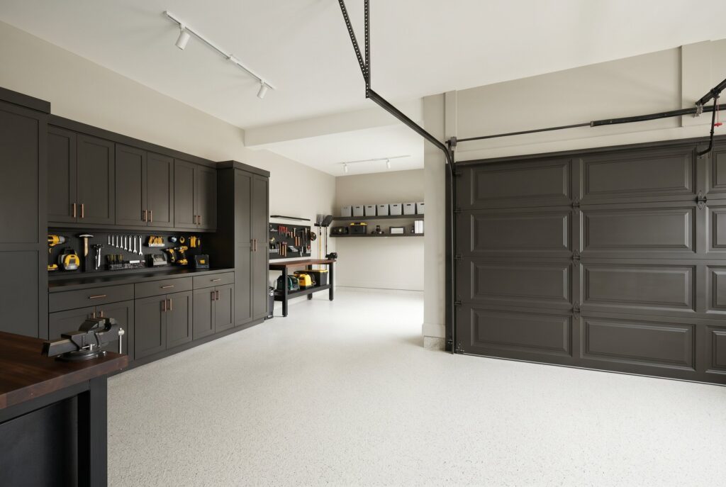 A garage painted in Sherwin Williams Urbane Bronze on the garage door and cabinet walls, providing a rich architectural look over a white floor.