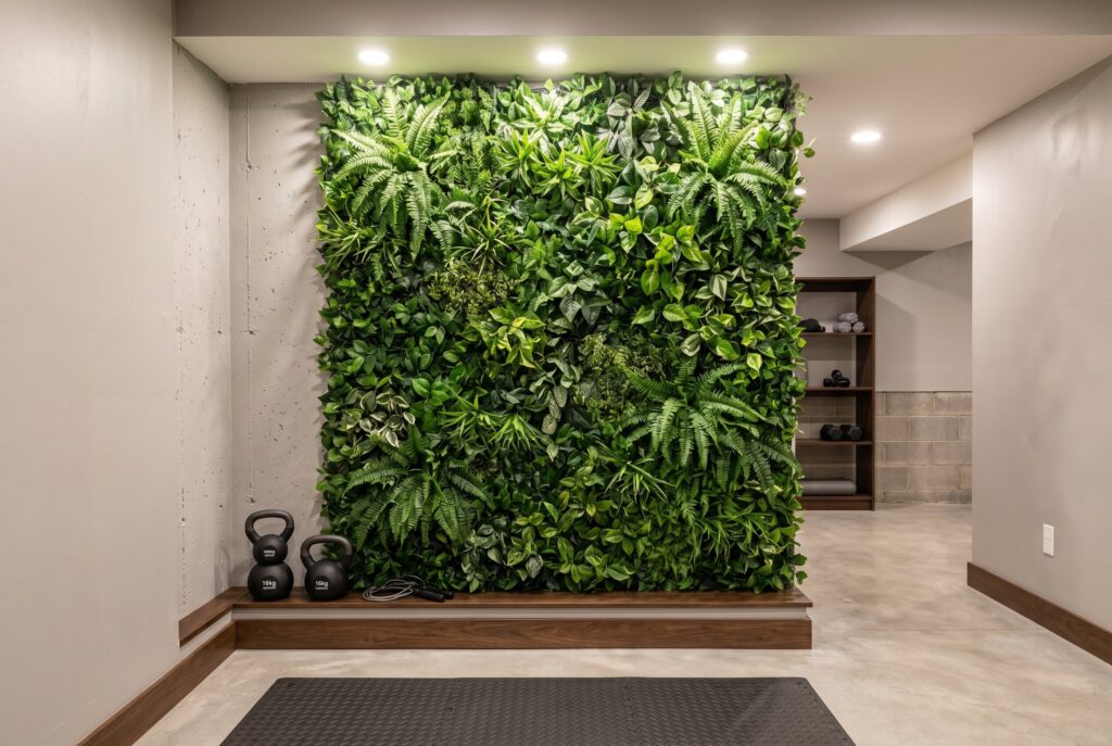 Faux greenery feature wall in windowless basement with workout equipment and seating area. 