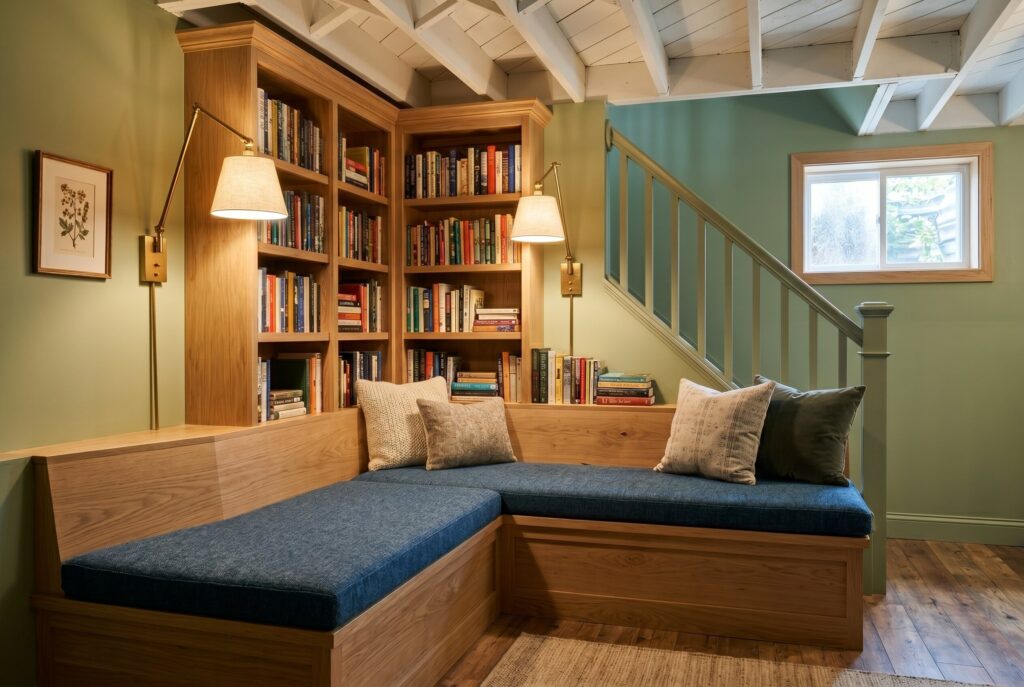 Reading den with built in bookshelves, cushioned bench seating, and warm sconces.