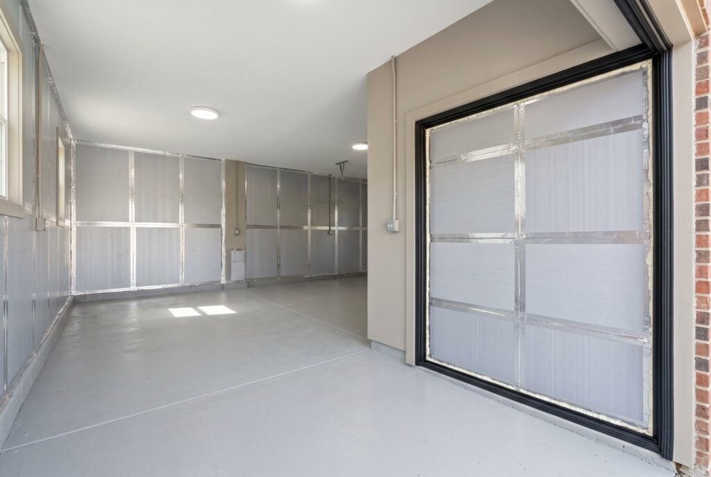 Finished garage with light gray epoxy flooring, insulated walls, and clean minimalist layout. 