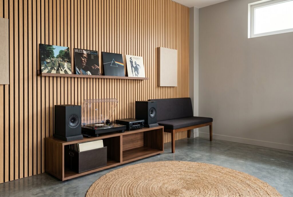 Minimalist listening room with walnut media console, record player, and acoustic slat backdrop. 
