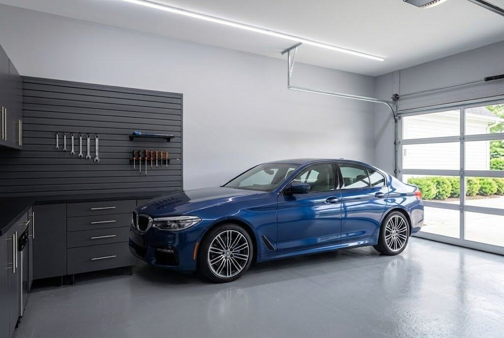 A garage painted in Behr Classic Silver, a light cool gray, contrasted with dark lower cabinets, black slatwall, a medium gray floor, and a blue BMW.