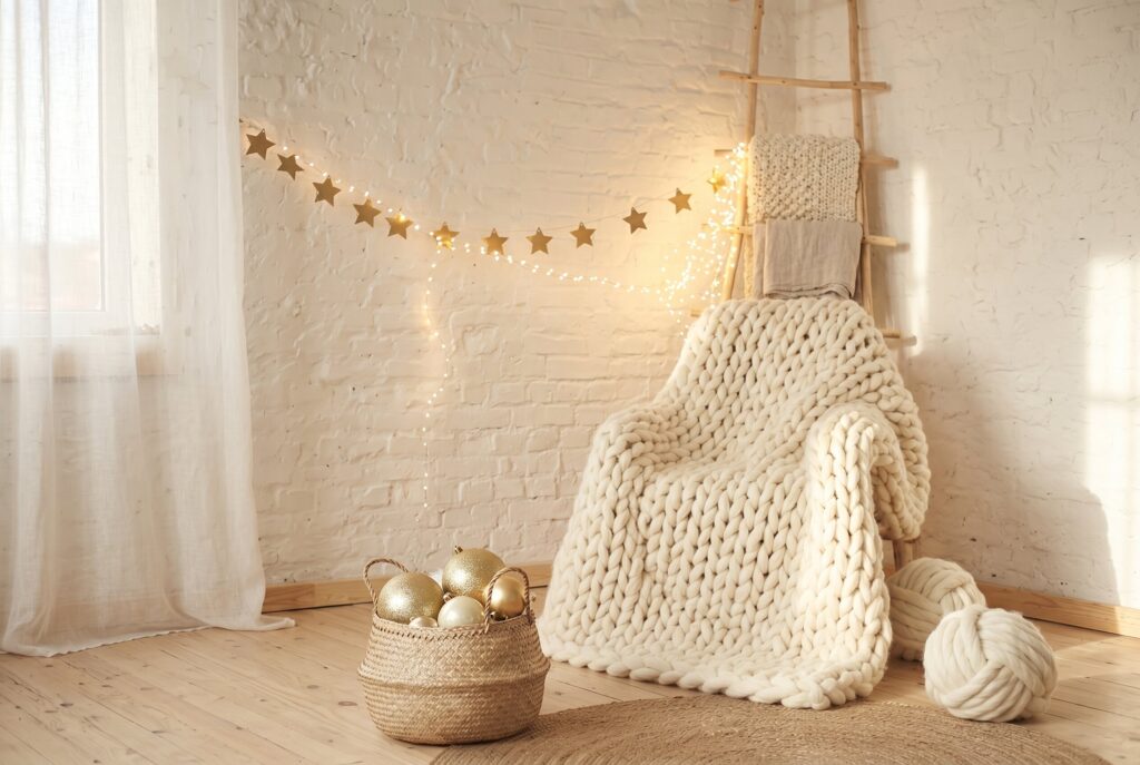 Chunky knit blanket draped on wood ladder in cozy reading corner.