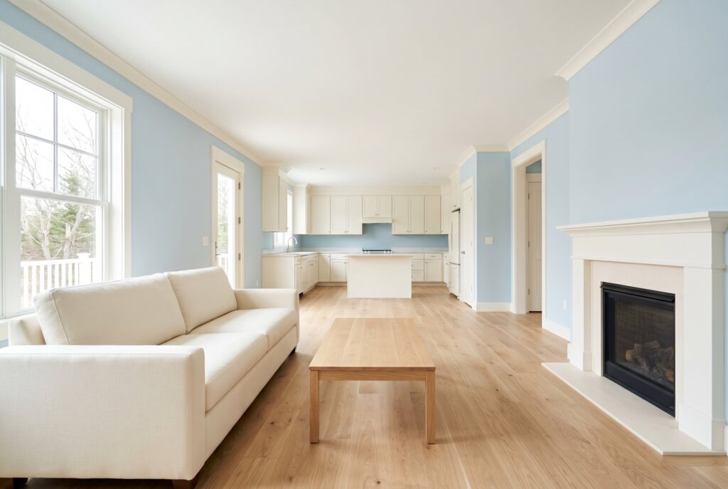 Pale blue living room with cream sofa, fireplace, and bright open plan layout. 