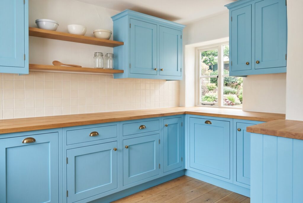 Robin’s Egg Blue kitchen cabinets with butcher block countertops, beadboard backsplash, and cottage styling.