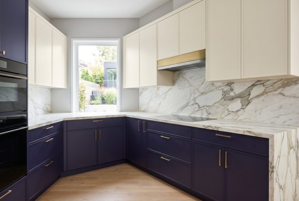 Midnight indigo two tone kitchen with deep indigo lower cabinets, cream uppers, and marble backsplash. 