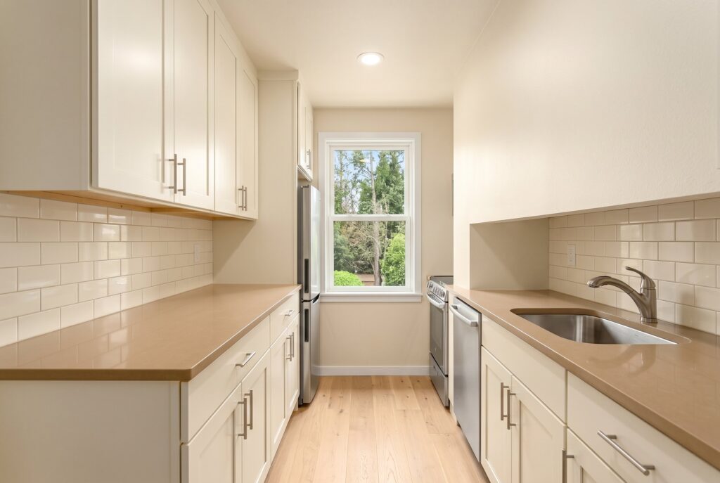 Warm white galley kitchen with cream cabinets, light countertops, and continuous wall to ceiling color.