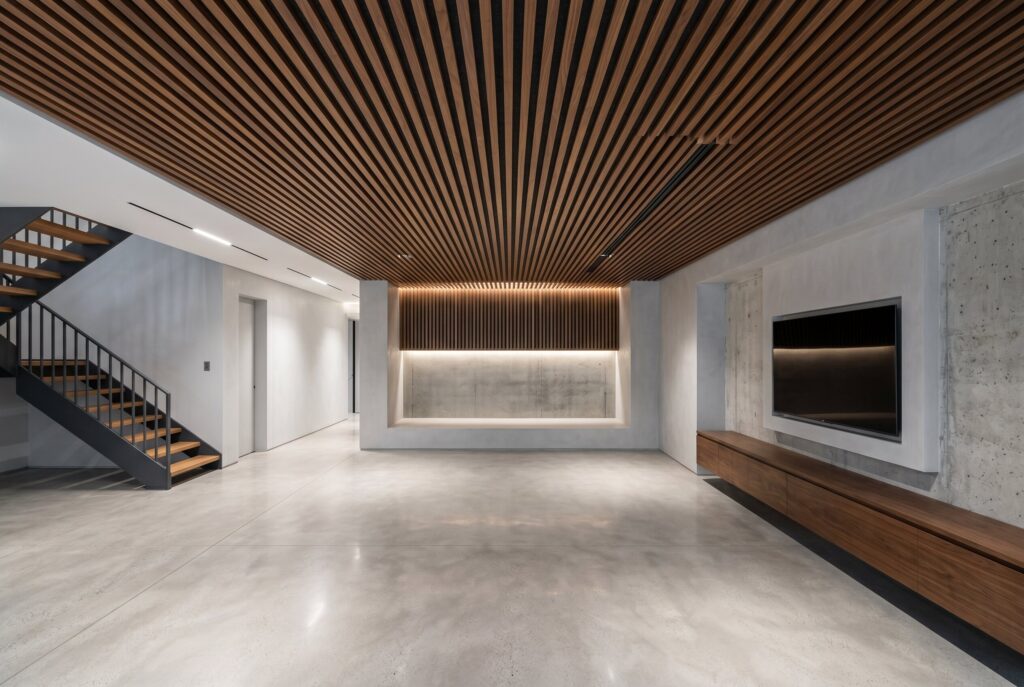 Acoustic walnut slat ceiling with integrated lighting and minimalist basement bar.