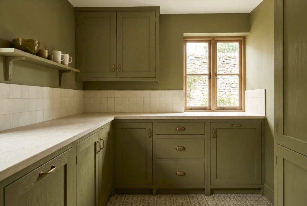 Olive green kitchen with matching cabinetry, white countertops, and warm traditional character.