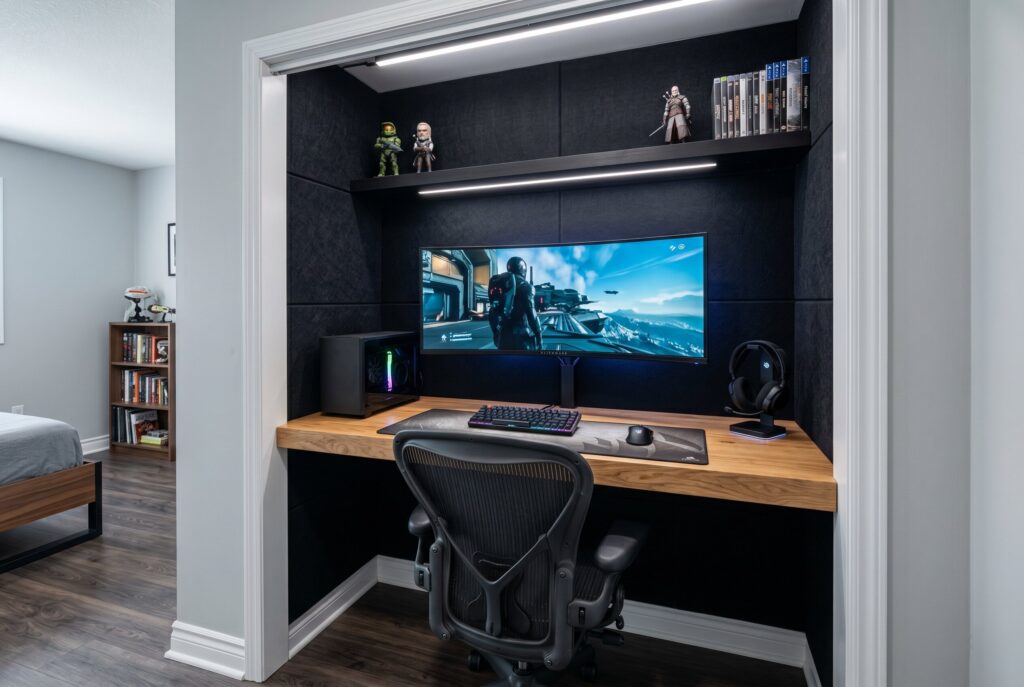 Closet converted into gaming station with floating oak desk, ultrawide monitor, and acoustic panels.