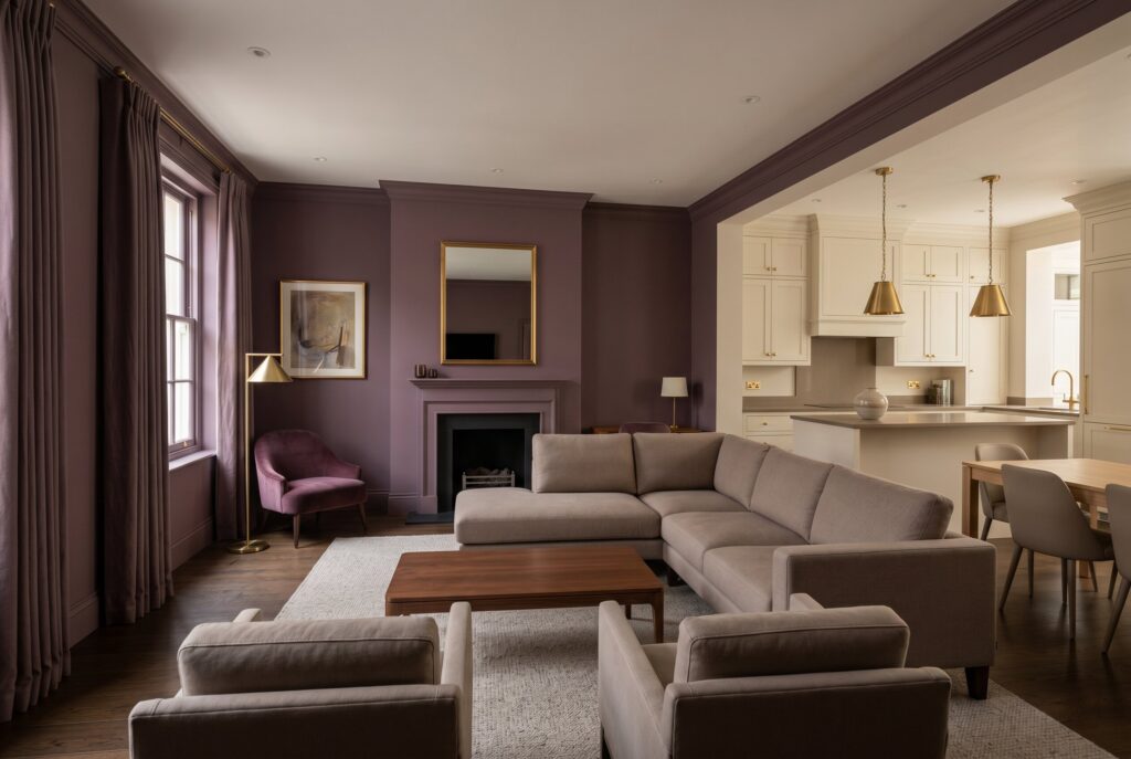Plum living room with taupe seating, dramatic drapery, and warm brass lighting. 
