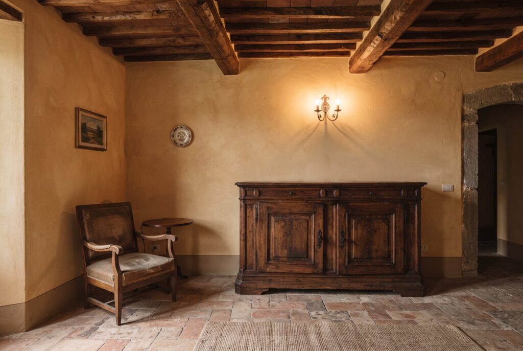 Tuscan room with warm ochre walls, dark wood ceiling, terracotta floors, a wooden cabinet.