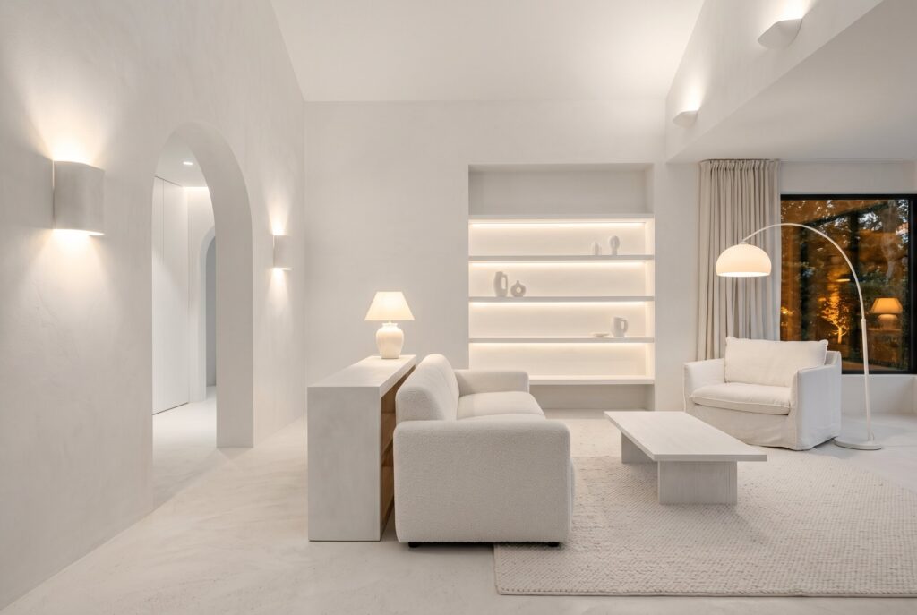 White living room featuring a curved sofa, soft textures, and layered neutral furnishings.