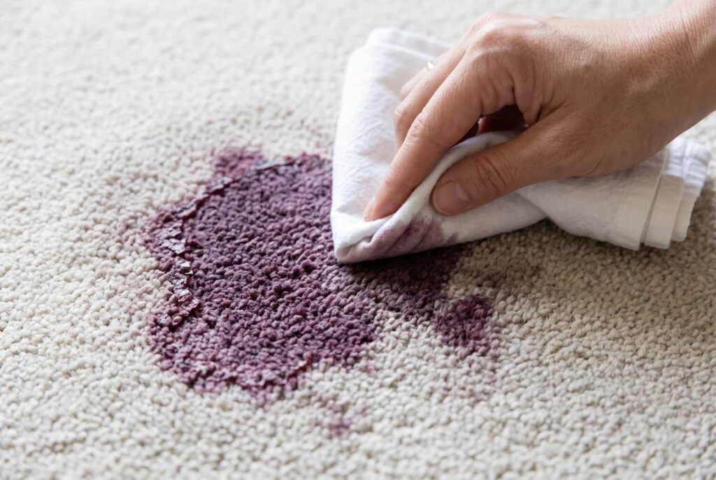 A dried red wine stain being blotted with a white cloth.