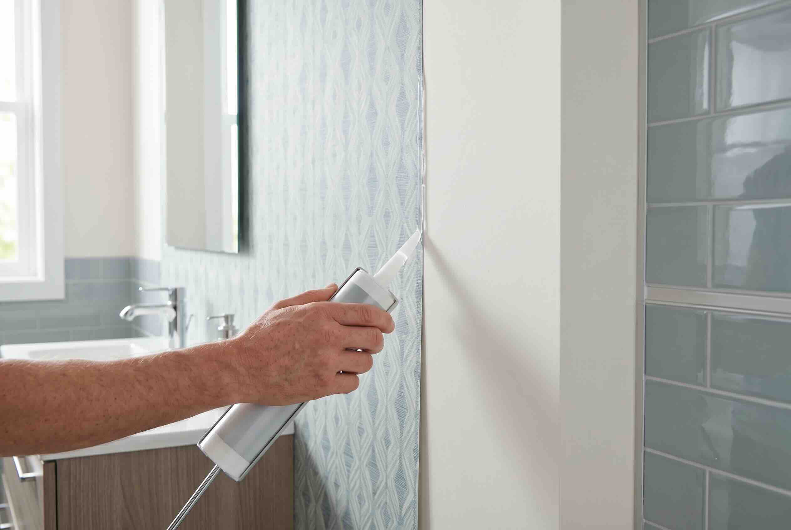 Sealing the edges of peel and stick wallpaper with clear caulk to block moisture.