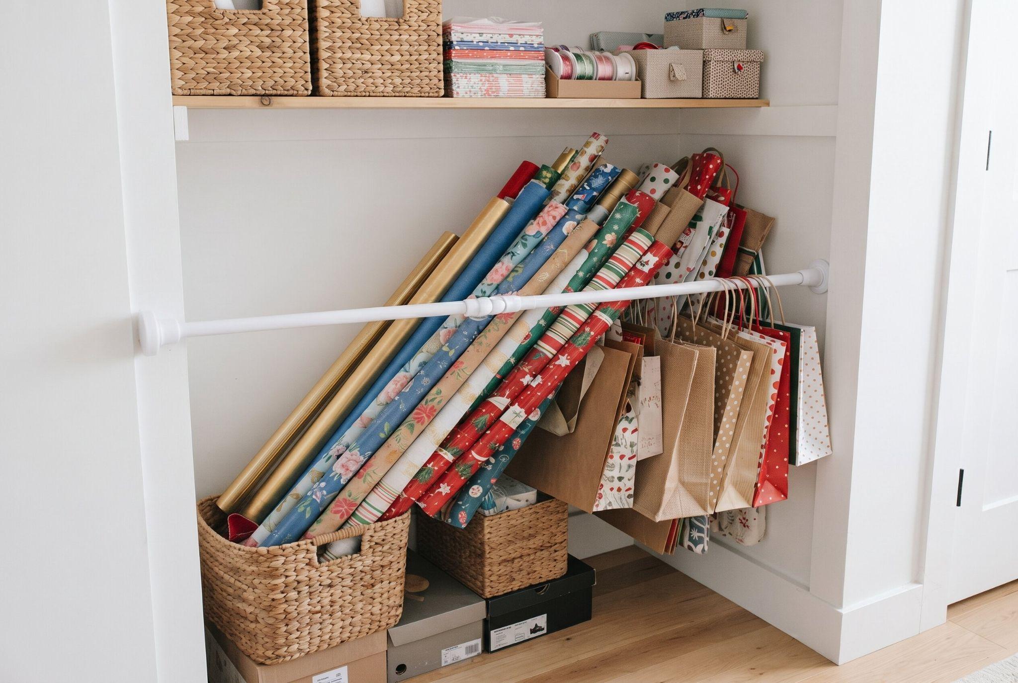 A white tension rod mounted diagonally across a closet corner to hold wrapping paper rolls.