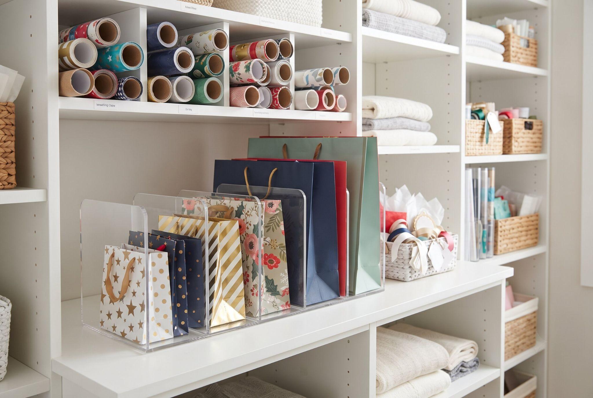 Acrylic file organizers on a shelf used to store gift bags upright, sorted by size.