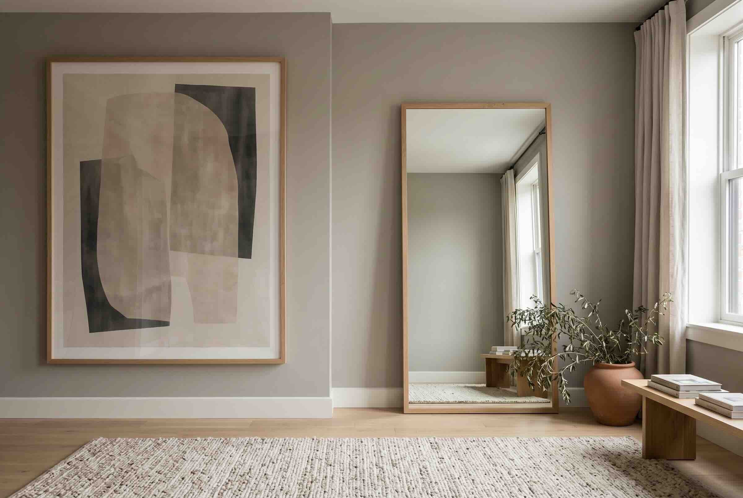 A leaning floor mirror next to oversized abstract wall art.