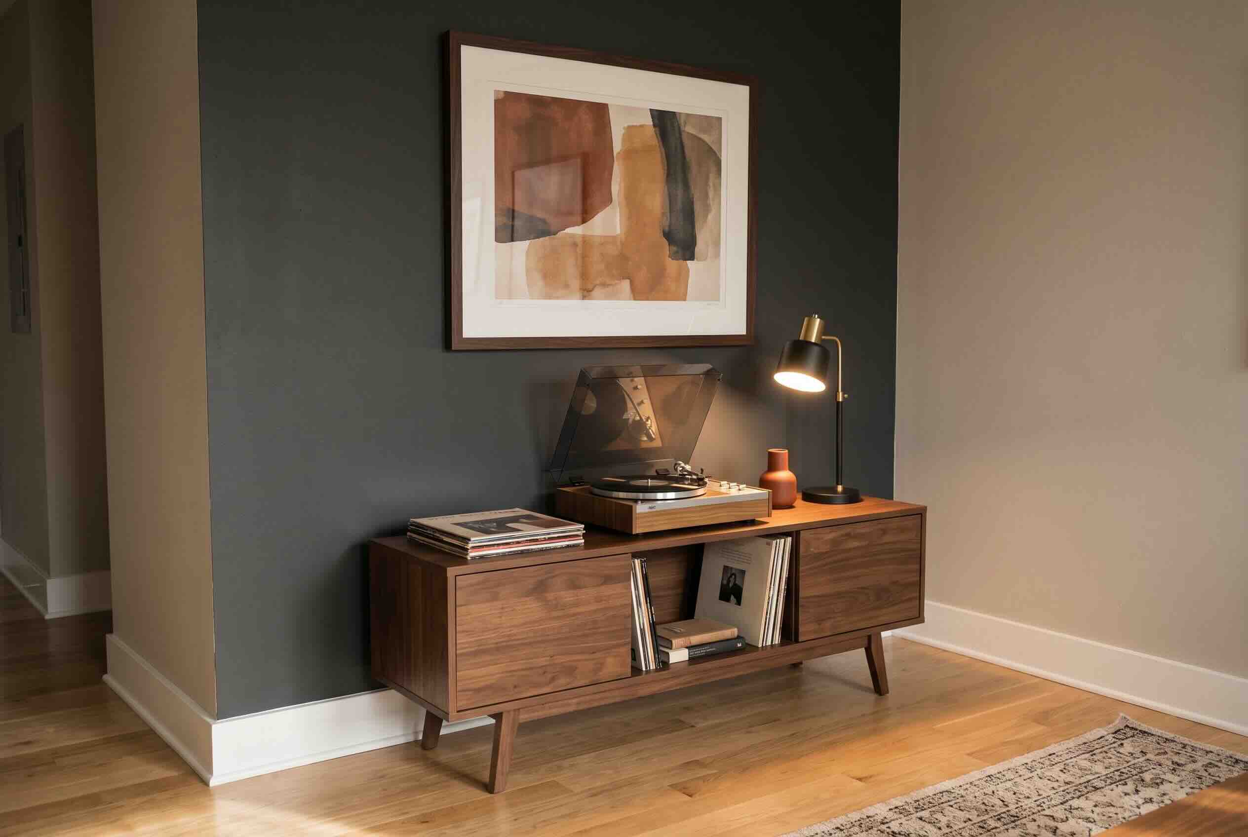 A wooden media console holding a record player and vinyl records under a framed piece of art.