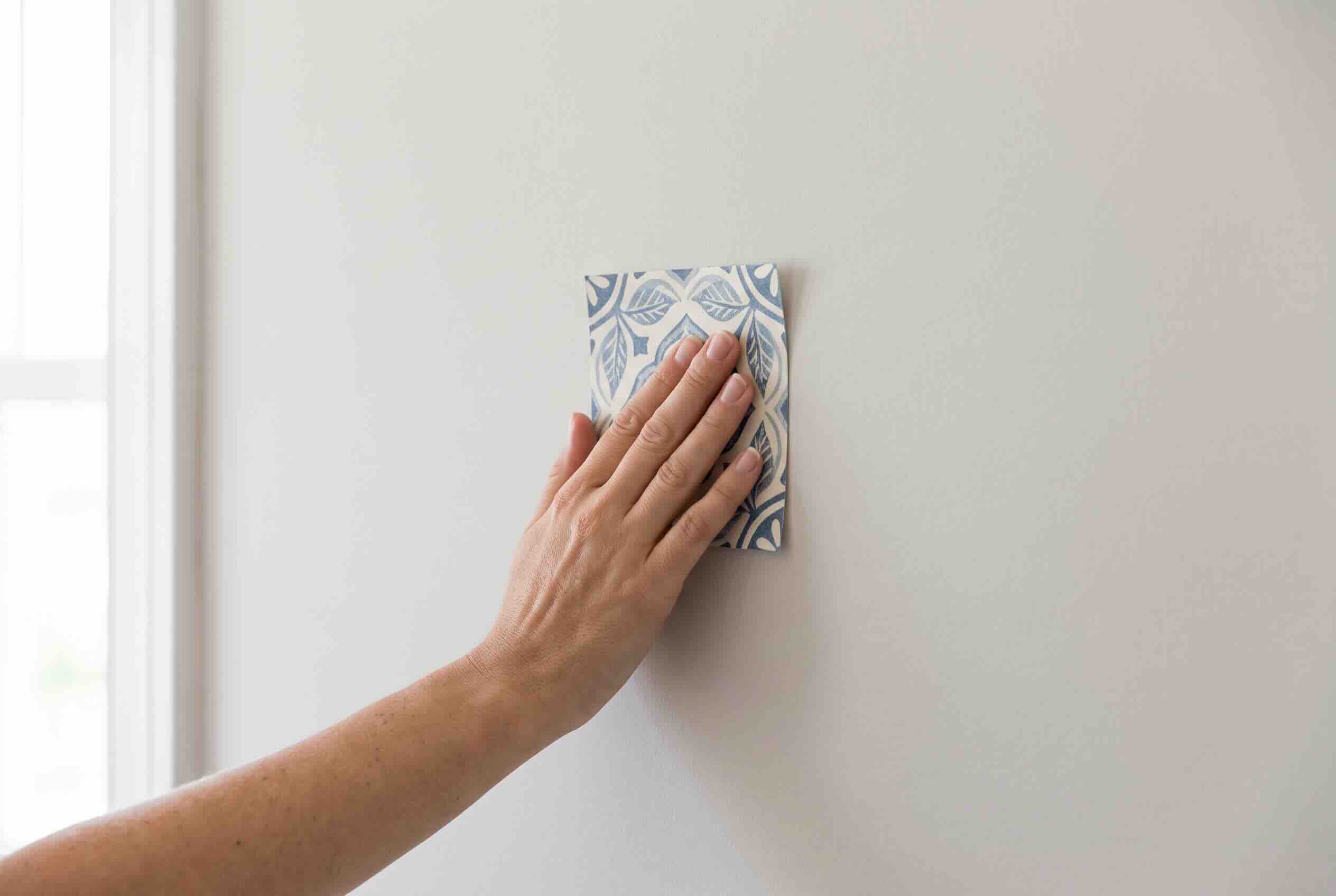 Applying a small swatch of peel and stick wallpaper to test adhesion.