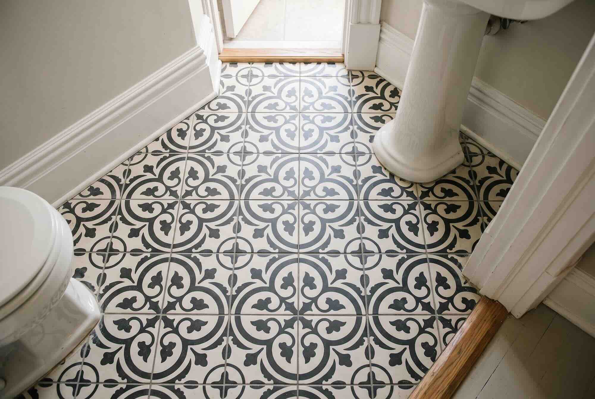 Bold, black-and-white patterned tile covering the floor of a small powder room.