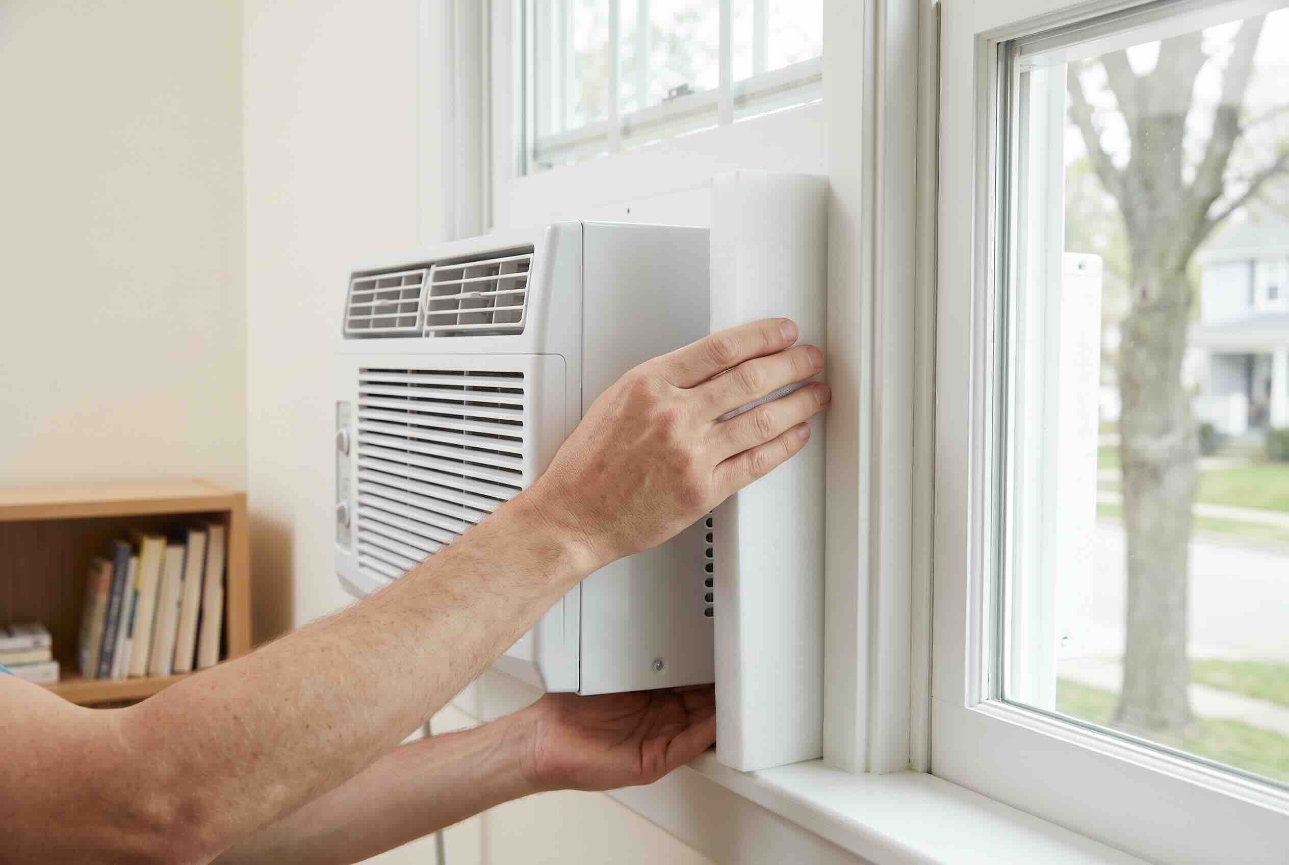 Installing rigid foam side panels around a window AC unit to seal gaps.