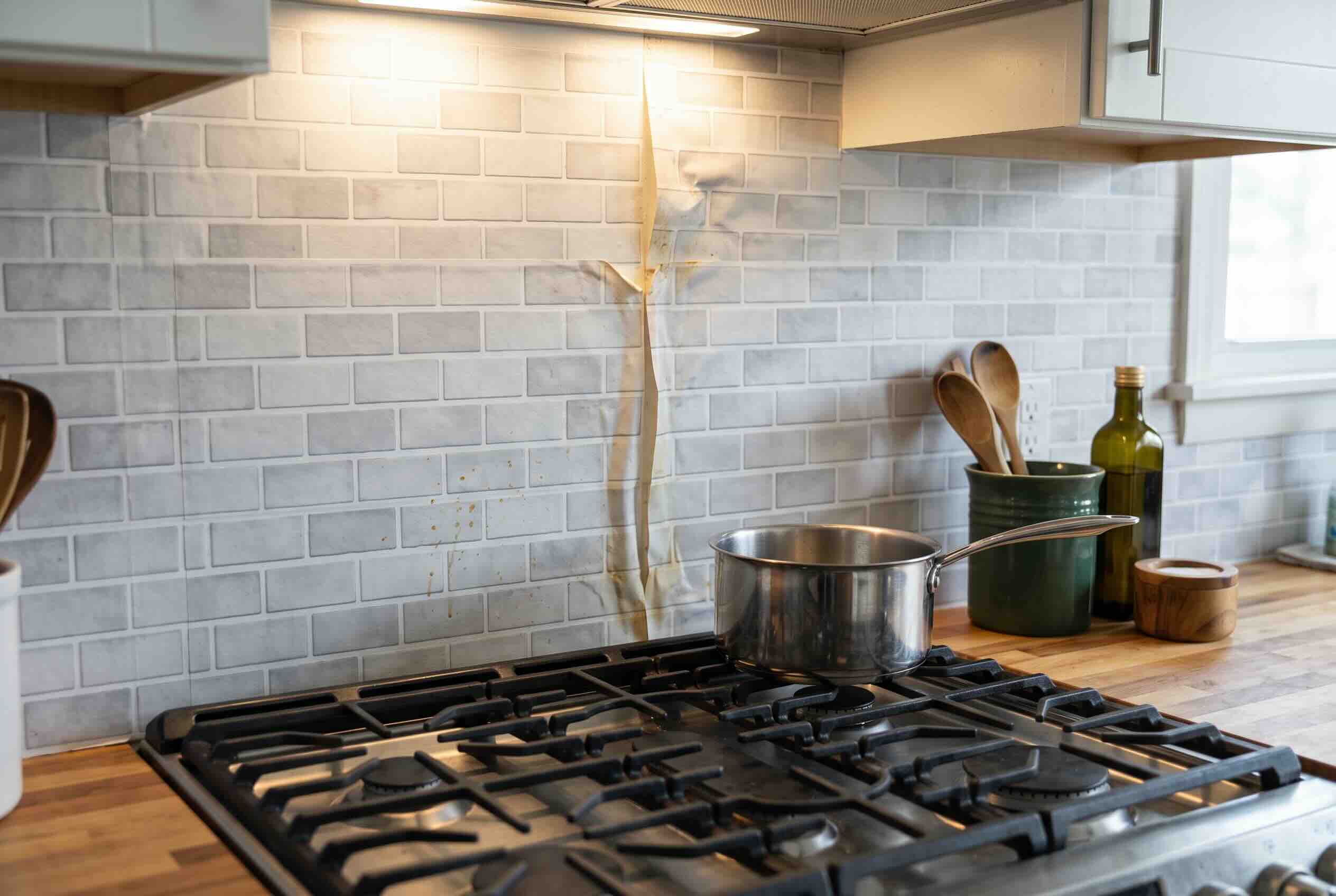 Peel and stick wallpaper used as a kitchen backsplash behind a stove.