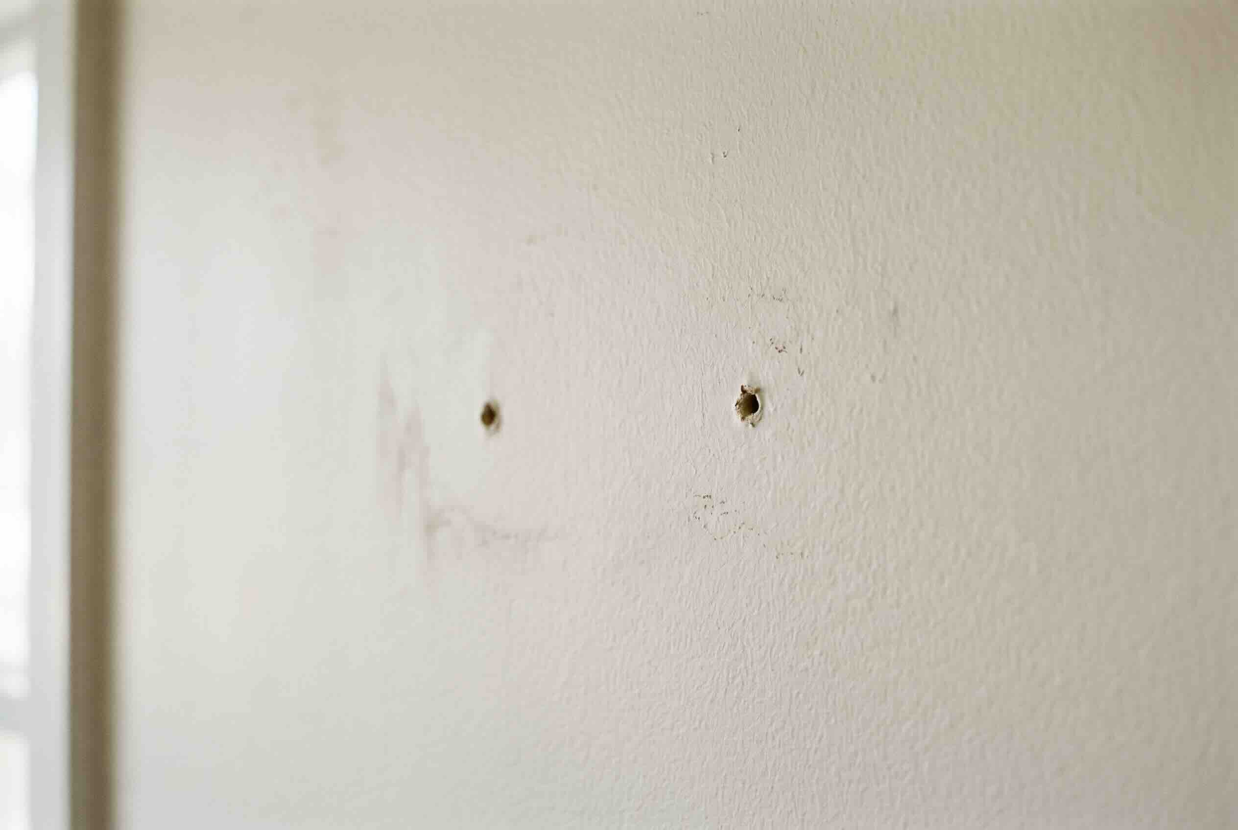 Small nail holes in a painted wall, which are considered normal wear and tear.