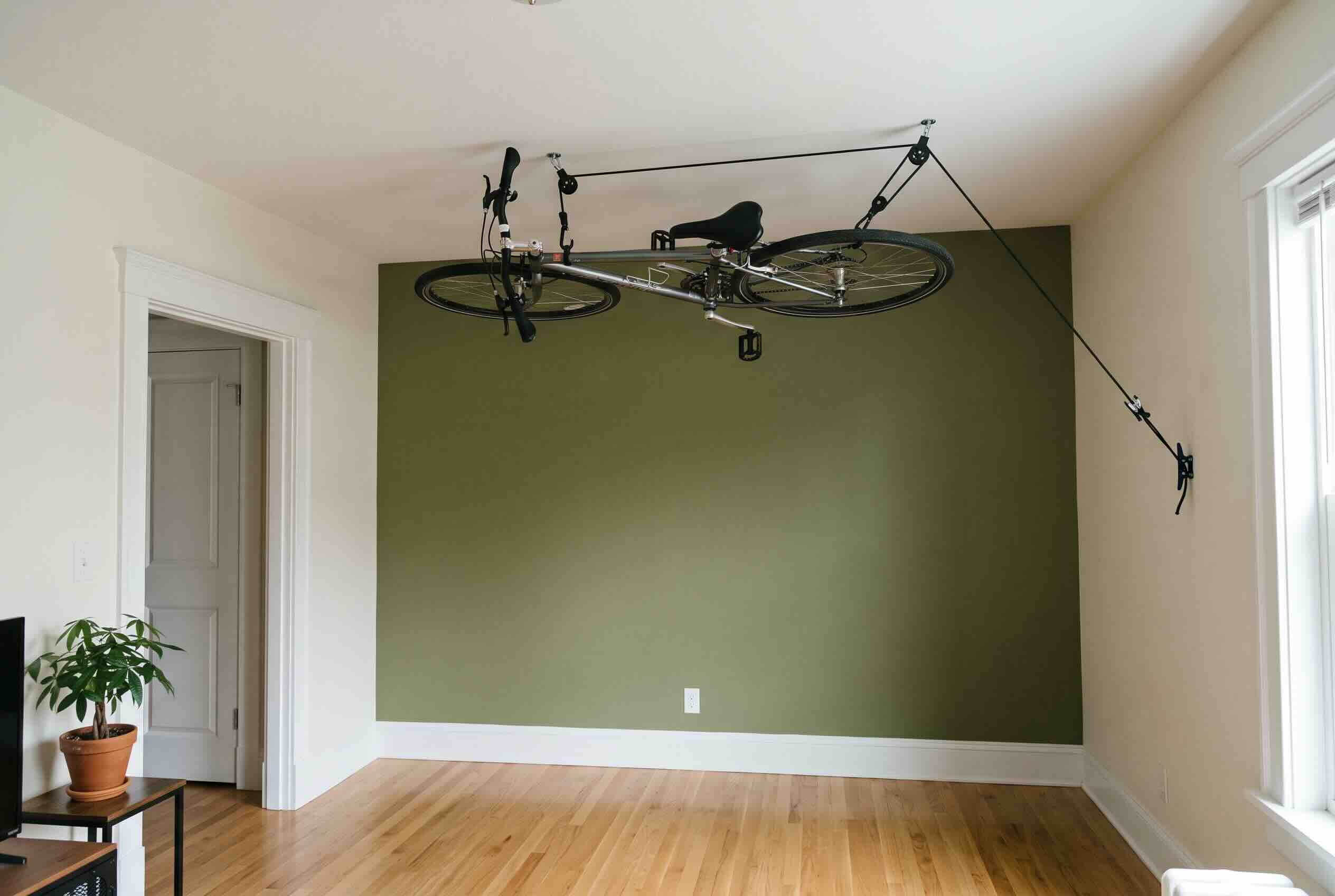 Suspending a bicycle flat against the ceiling using a pulley hoist system.
