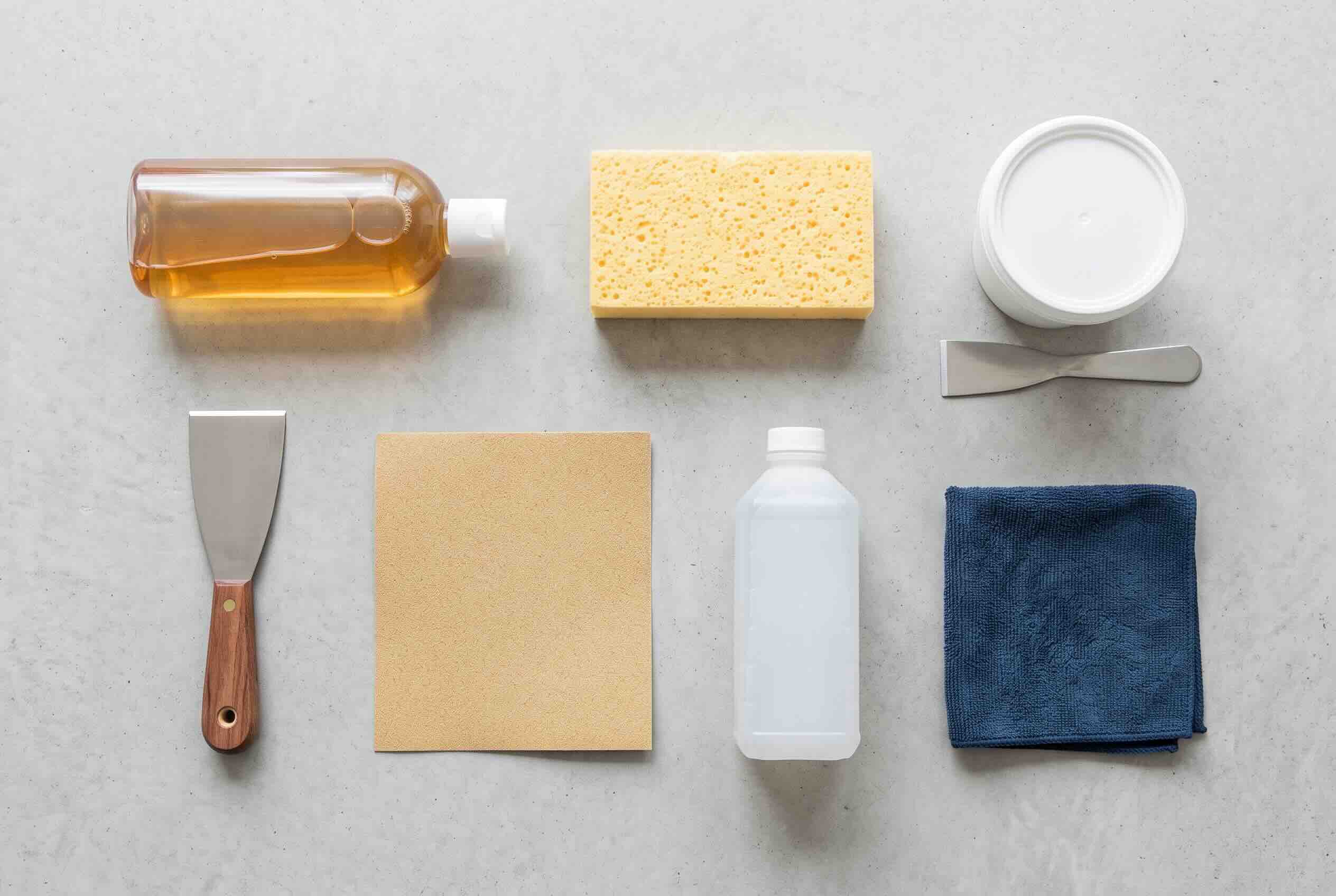 Wallpaper preparation tools including rubbing alcohol, a putty knife, a sponge, spackle, and a tack cloth.